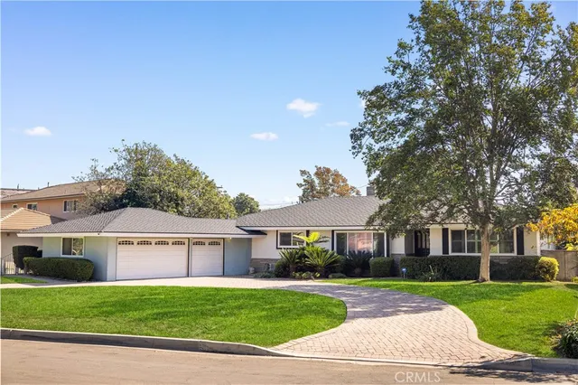 a front view of a house with a garden and trees