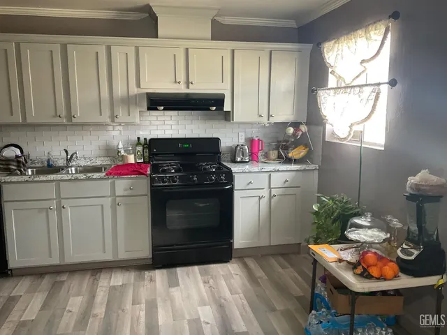 a kitchen with stainless steel appliances granite countertop a stove a sink and white cabinets