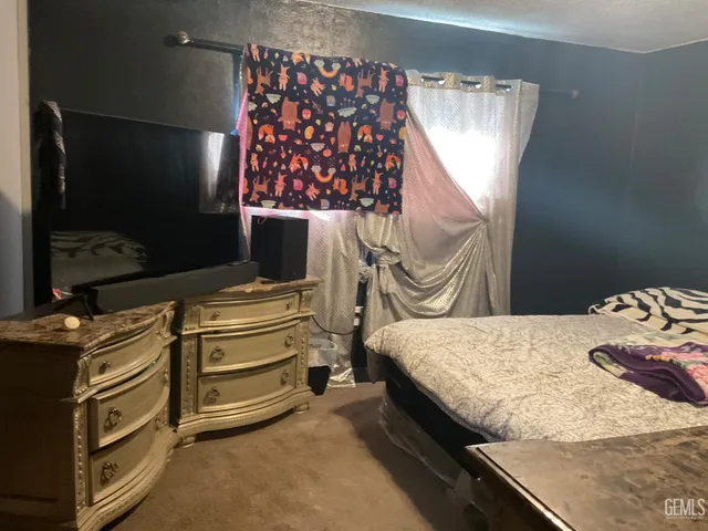 a bedroom with a bed and a flat tv screen on dresser