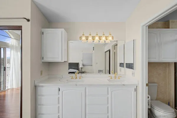 a bathroom with double vanity sink a toilet and a mirror
