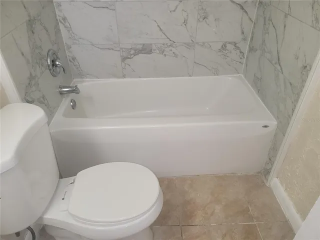 a bathroom with a white toilet and bathtub