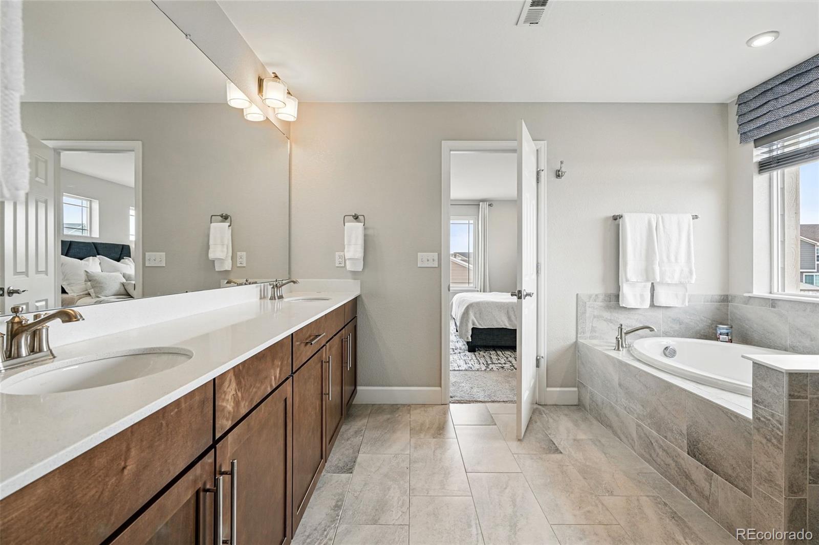 745 Penstemon Drive Henderson, CO 80640 - Photo 16 of 38 a spacious bathroom with a double vanity sink a mirror and a bathtub