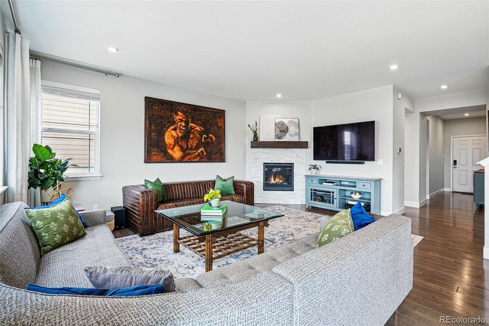 745 Penstemon Drive Henderson, CO 80640 - Photo 5 of 38 a living room with furniture a fireplace a flat screen tv and potted plant