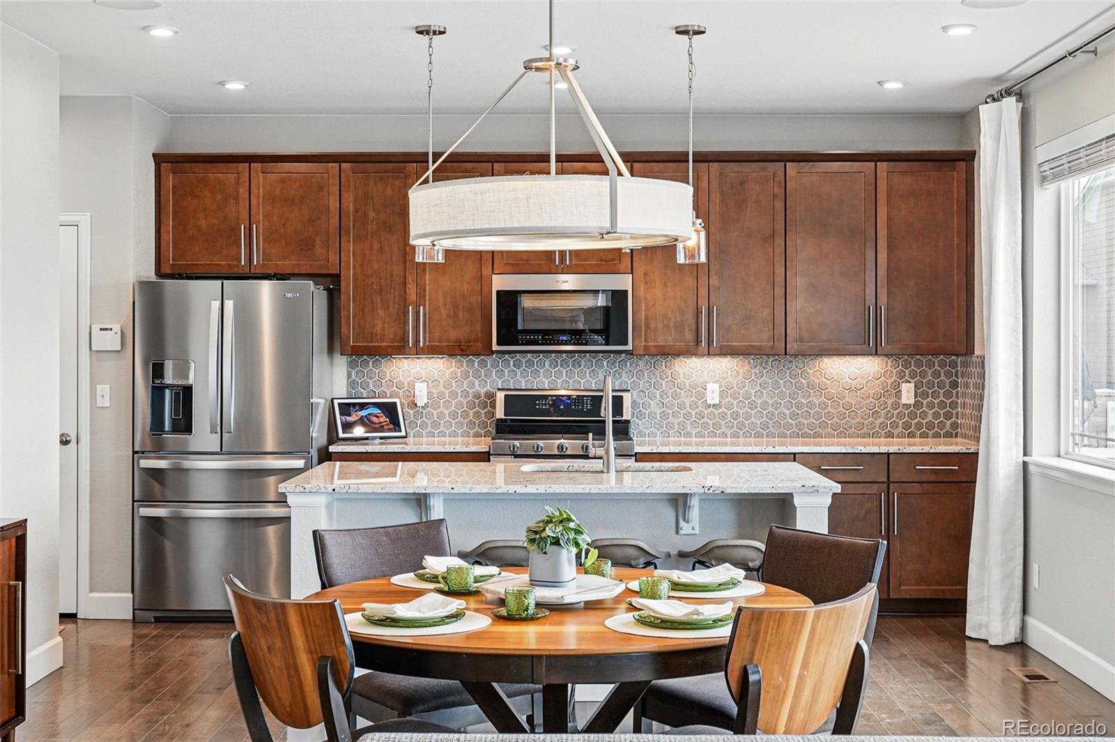 745 Penstemon Drive Henderson, CO 80640 - Photo 8 of 38 a kitchen with stainless steel appliances granite countertop a refrigerator a stove a sink a dining table and chairs