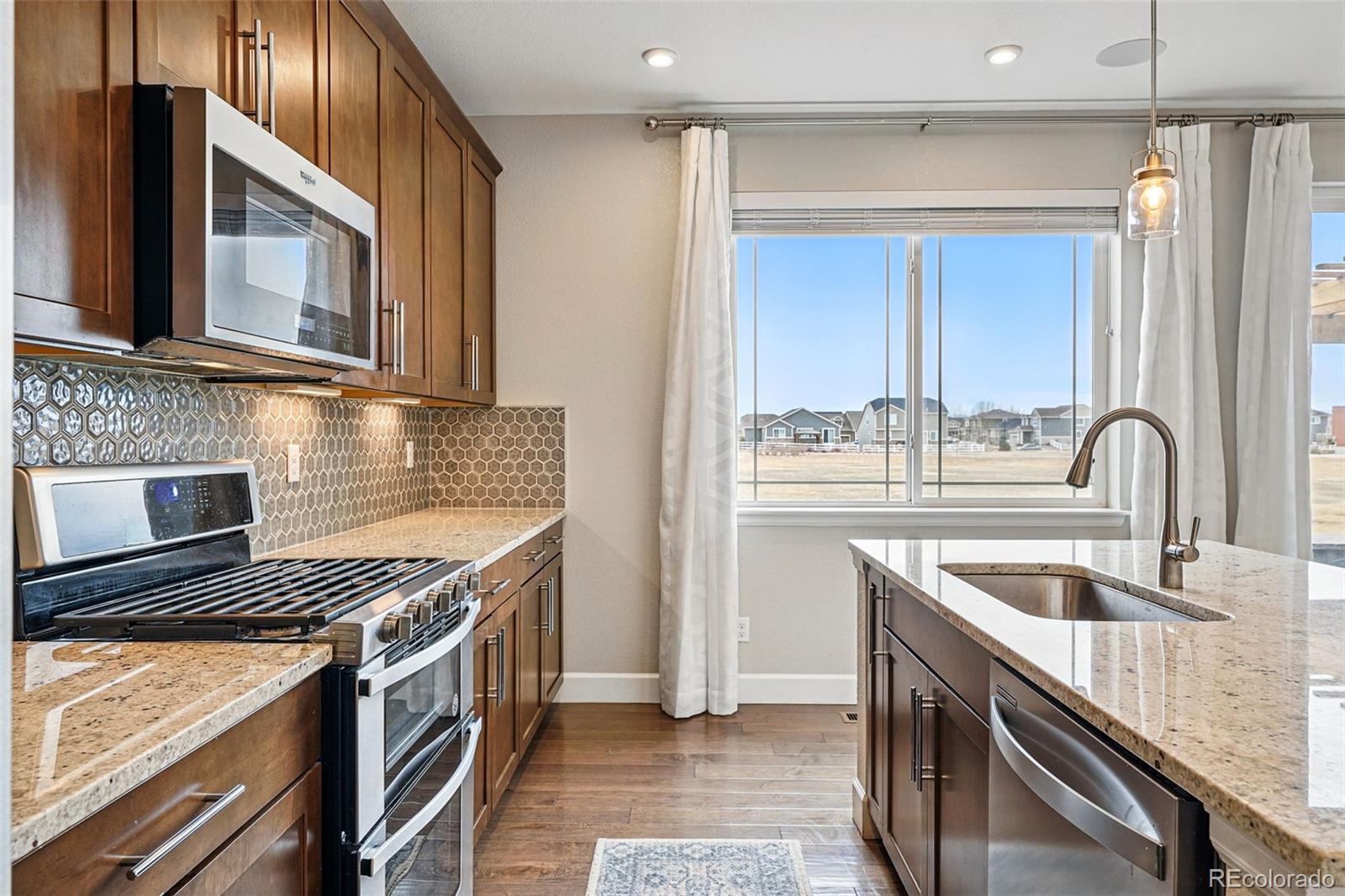 745 Penstemon Drive Henderson, CO 80640 - Photo 10 of 38 a kitchen with stainless steel appliances granite countertop a sink and a stove