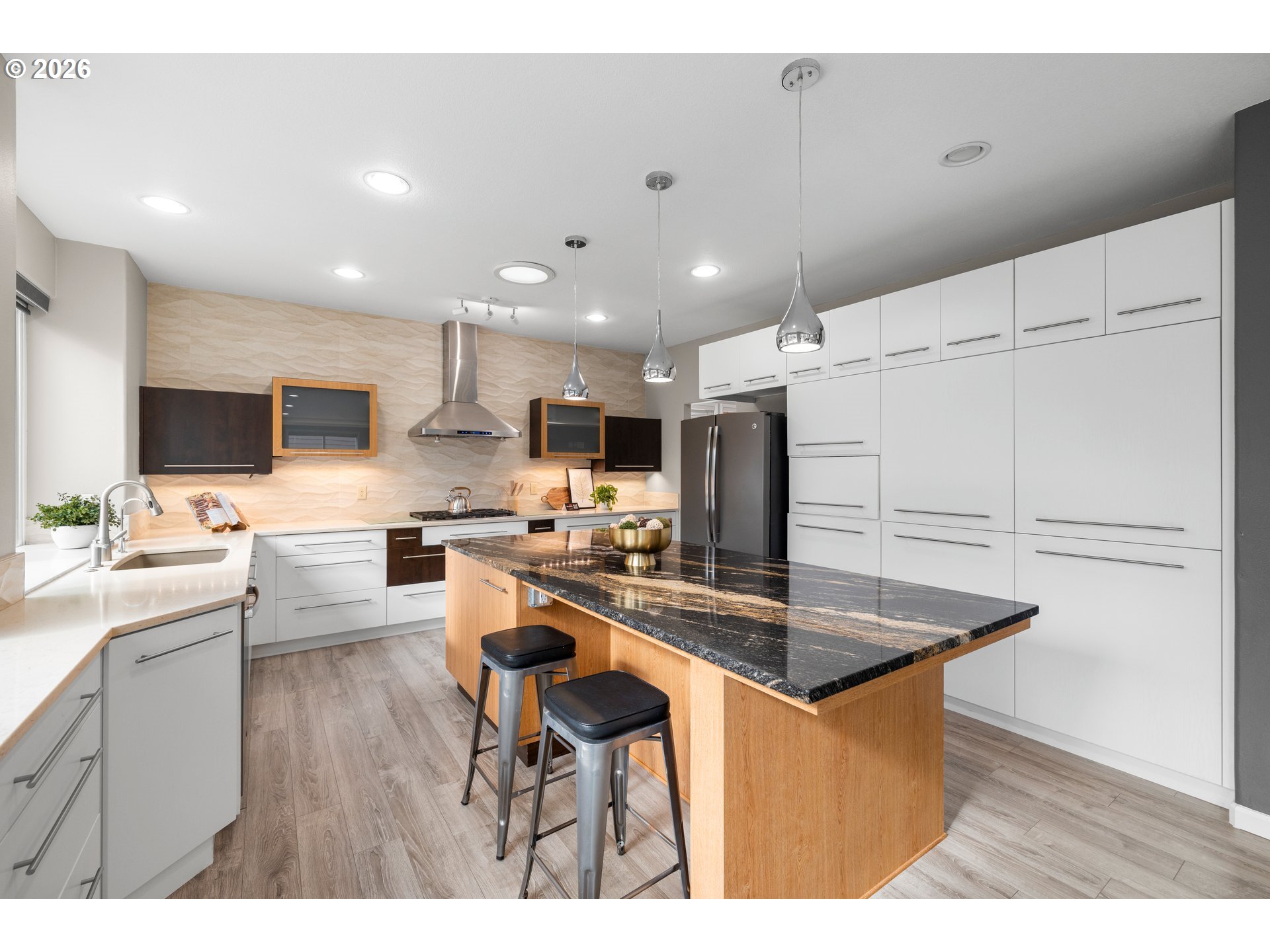 15542 Northwest Andalusian Way Portland, OR 97229 - Photo 21 of 48 a kitchen with kitchen island a stove a sink a refrigerator and white cabinets with wooden floor