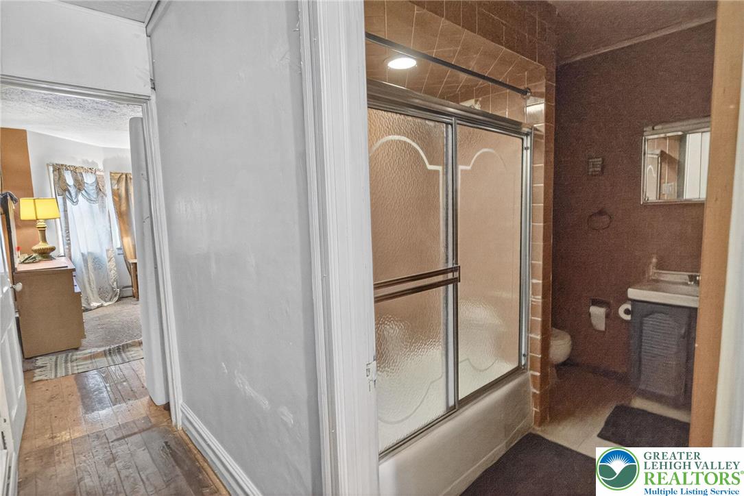 19 East Patterson Street Lansford, PA 18232 - Photo 12 of 17 a bathroom with a glass shower door and a mirror