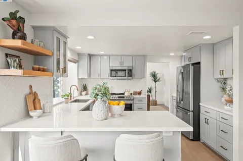 a kitchen with a sink dishwasher a refrigerator and white cabinets with wooden floor