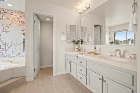 a bathroom with a double vanity sink mirror and bathtub