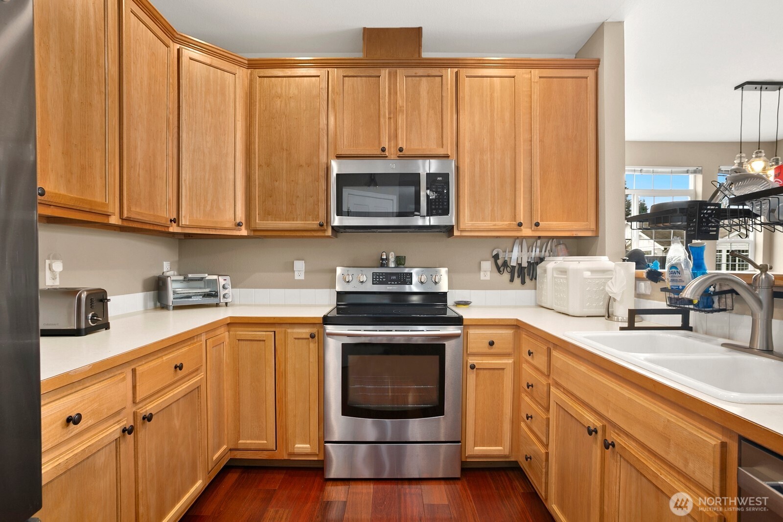 6830 20th Street East, Unit F5 Fife, WA 98424 - Photo 12 of 25 a kitchen with granite countertop wooden cabinets a sink and a stove with wooden floor