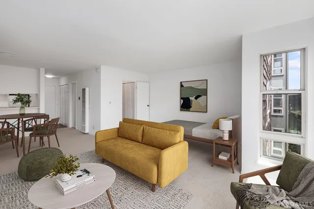 a living room with furniture potted plant and kitchen view