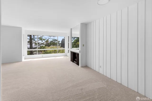 a view of an empty room with a fireplace and a window