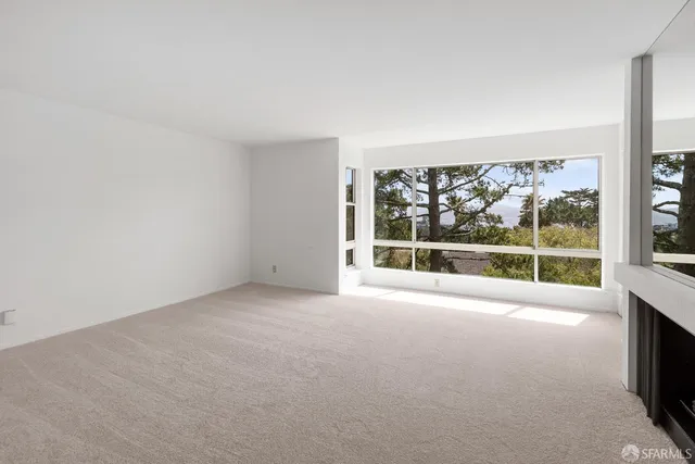 an empty room with floor to ceiling window and an outdoor view