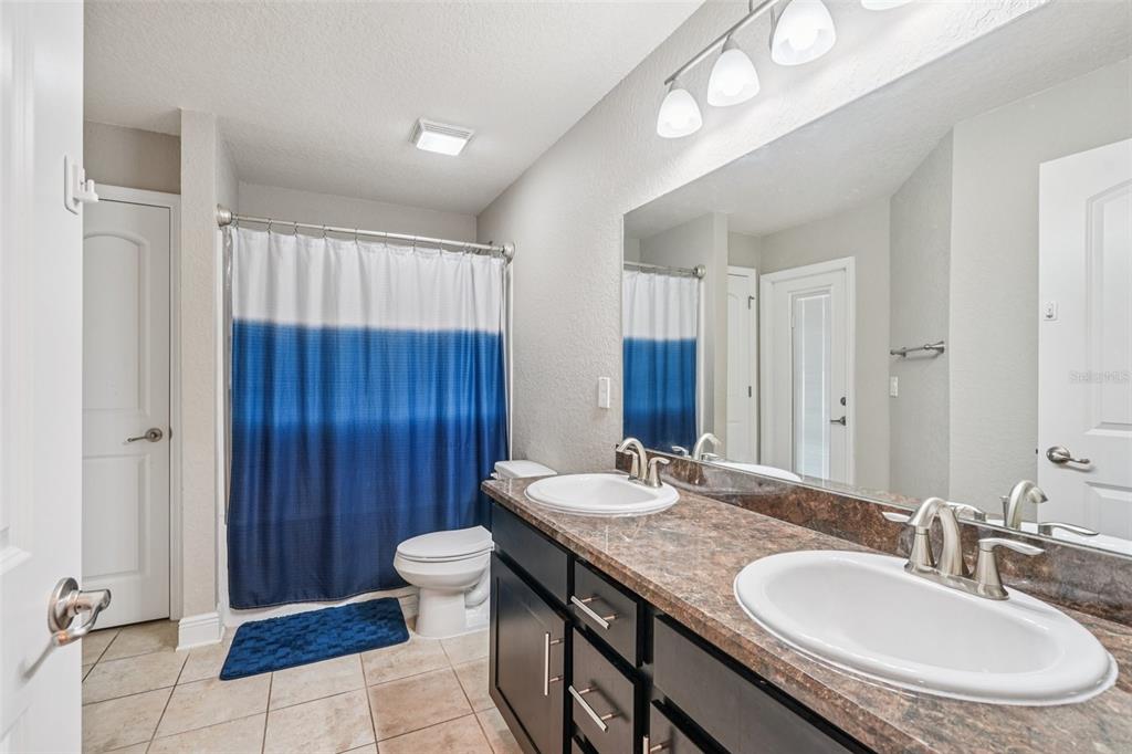 9846 Southwest 55th Ave Road Ocala, FL 34476 - Photo 18 of 25 a bathroom with a granite countertop double vanity sink a mirror and a toilet