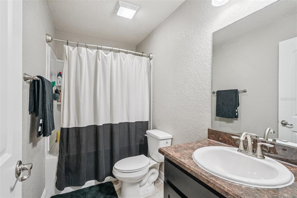 9846 Southwest 55th Ave Road Ocala, FL 34476 - Photo 20 of 25 a bathroom with a sink a toilet a mirror and shower curtain