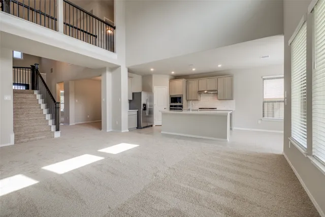 a living room with stainless steel appliances kitchen island furniture and windows