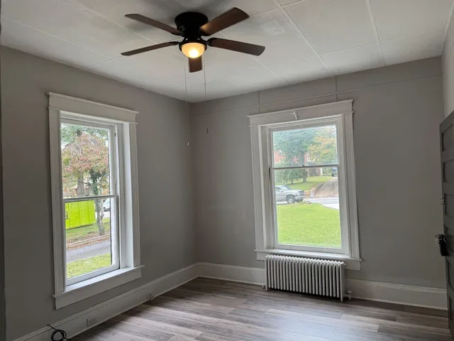an empty room with window and a ceiling fan