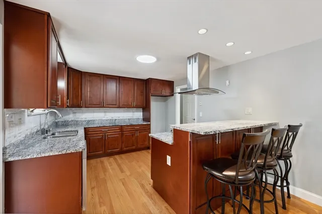 a kitchen with stainless steel appliances granite countertop a kitchen island a stove a sink dishwasher a dining table and chairs with wooden floor