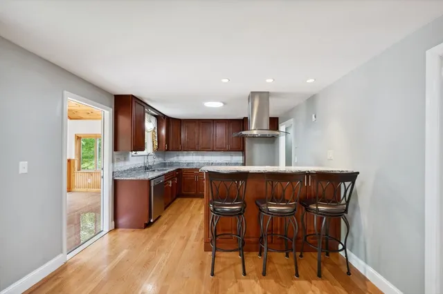 a kitchen with stainless steel appliances granite countertop a kitchen island hardwood floor sink and stove