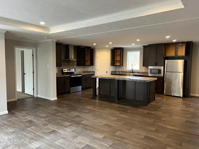 a kitchen with stainless steel appliances granite countertop a stove top oven a sink and a refrigerator