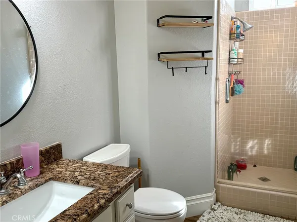 a bathroom with a granite countertop sink a toilet and shower