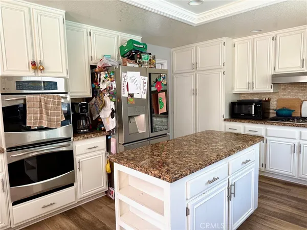 a kitchen with granite countertop a sink stainless steel appliances and white cabinets