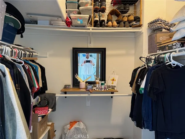 a view of walk in closet with clothes and shoes