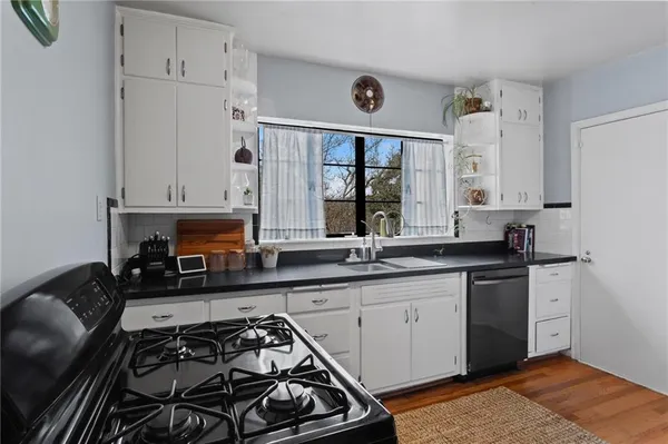 a kitchen with stainless steel appliances a stove a sink and white cabinets