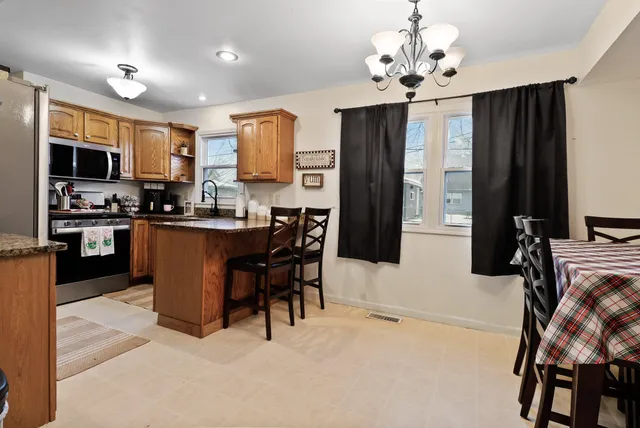 a kitchen with stainless steel appliances kitchen island granite countertop a refrigerator a stove top oven a sink dishwasher and white cabinets with wooden floor