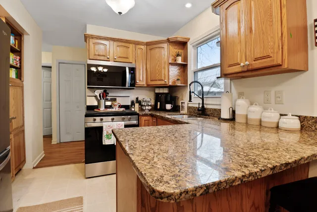 a kitchen with granite countertop a stove a sink a refrigerator and a cabinets