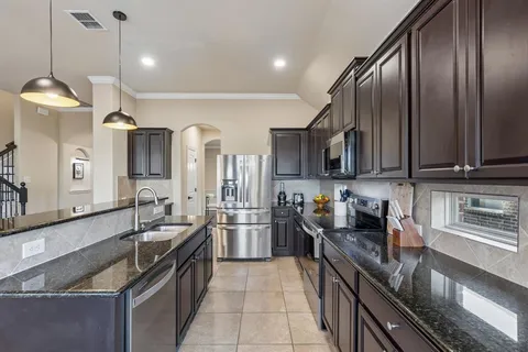 a kitchen with stainless steel appliances granite countertop a sink stove and refrigerator