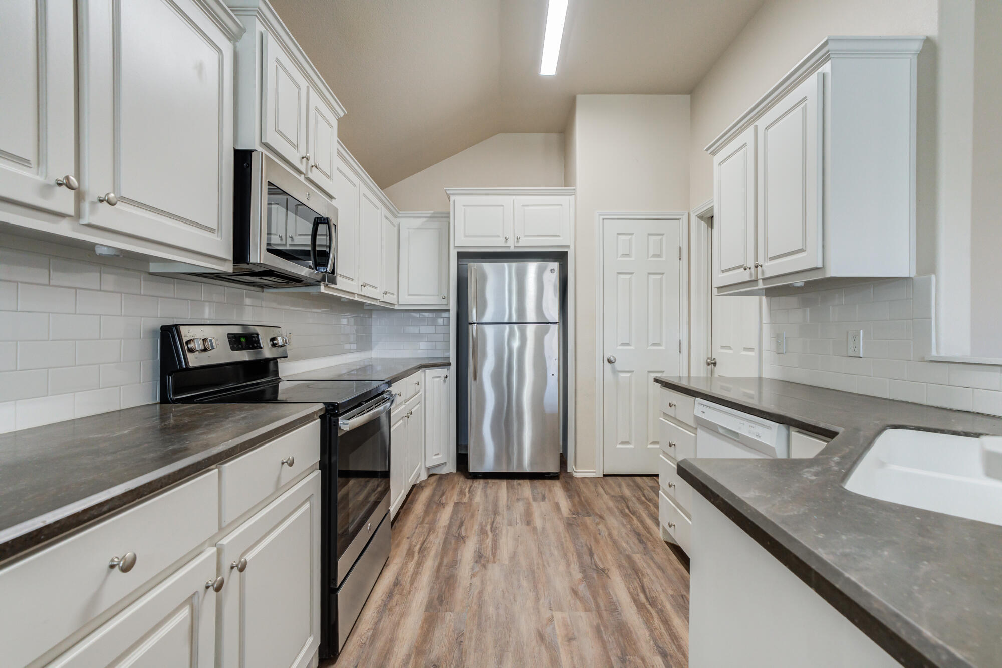 7518 87th Street Lubbock, TX 79424 - Photo 13 of 36 a kitchen with stainless steel appliances granite countertop a sink stove and refrigerator