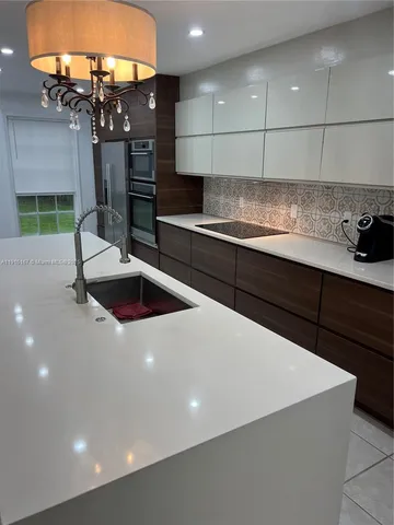 a kitchen with stainless steel appliances a sink a counter top space cabinets and a fireplace