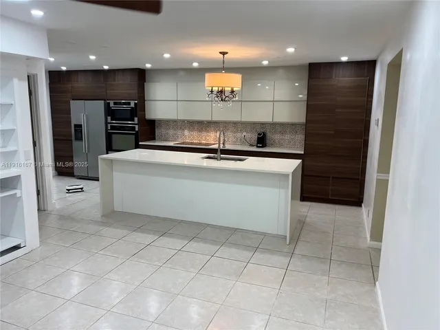a view of kitchen with stainless steel appliances kitchen island granite countertop a sink and cabinets