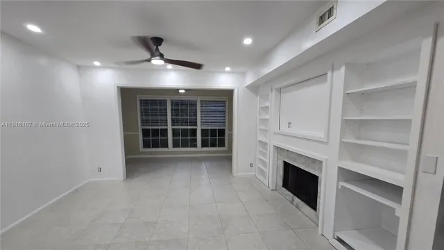 a view of an empty room with a fireplace and a window