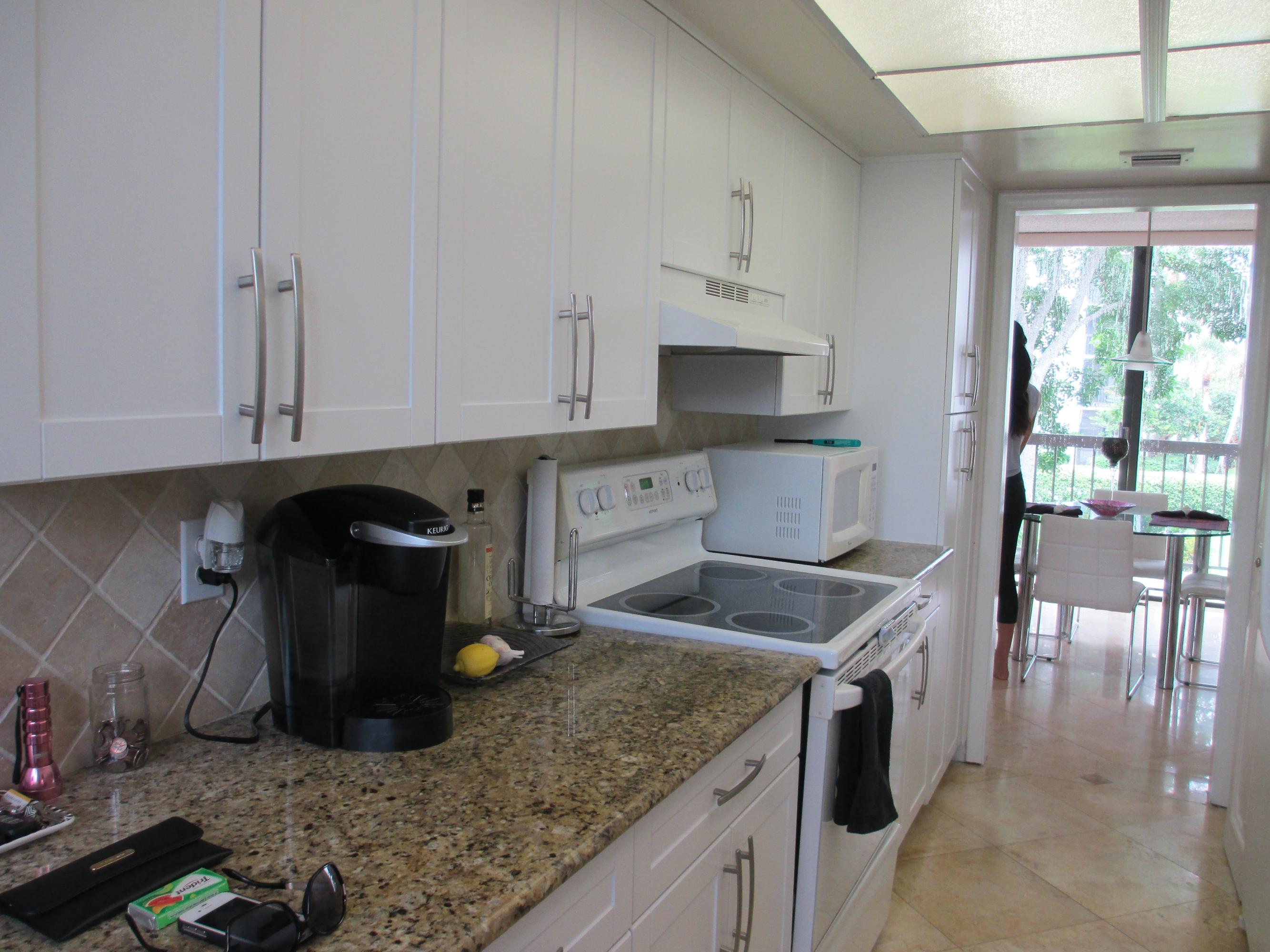 1405 Bridgewood Drive, Unit 1405 Boca Raton, FL 33434 - Photo 13 of 54 a kitchen with a sink and white cabinets