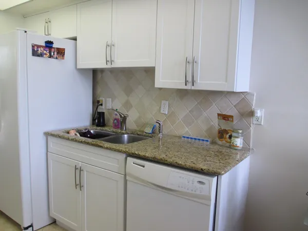 a kitchen with granite countertop white cabinets and a sink