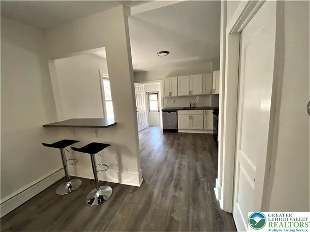 a view of a kitchen with kitchen island stainless steel appliances wooden floor and view living room