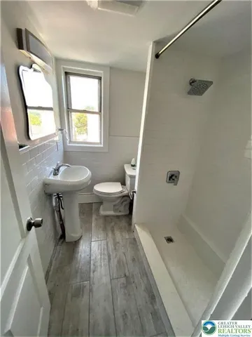 a bathroom with a sink a toilet and shower