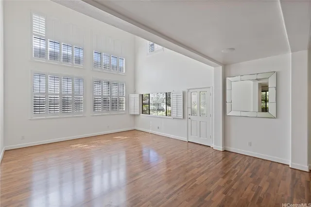 a view of an empty room with wooden floor and windows