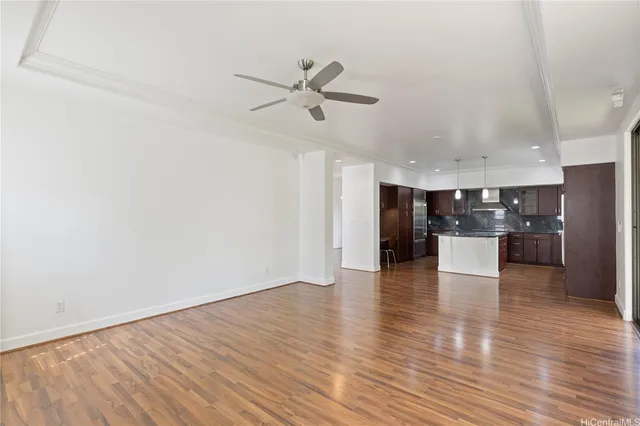 a view of a kitchen and an empty room with wooden floor