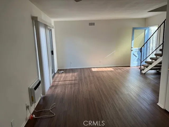 an empty room with wooden floor and staircase
