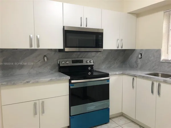 a kitchen with granite countertop a stove and a microwave
