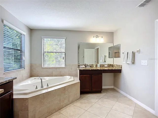 a spacious bathroom with a tub sink and mirror
