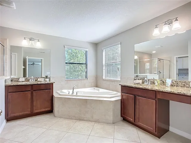 a bathroom with a granite countertop bathtub sink and mirror