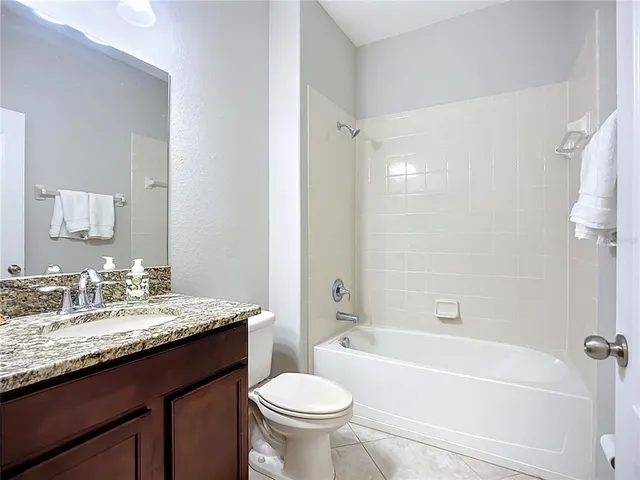 a bathroom with a granite countertop sink a toilet a mirror and a bathtub