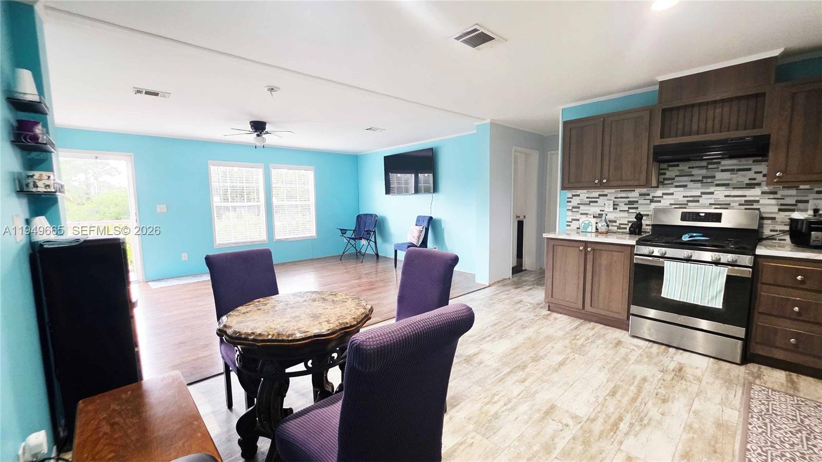 612 Hunting Clb Avenue Clewiston, FL 33440 - Photo 19 of 36 a kitchen with stainless steel appliances kitchen island granite countertop a stove a sink dishwasher a dining table and chairs with wooden floor