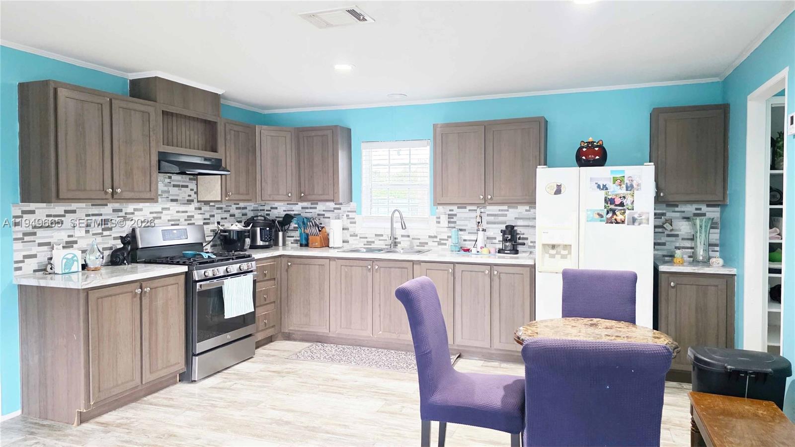 612 Hunting Clb Avenue Clewiston, FL 33440 - Photo 20 of 36 a kitchen with stainless steel appliances granite countertop a stove a sink a microwave a refrigerator and chairs