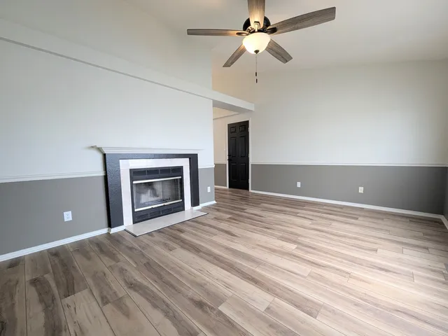 an empty room with chandelier fan and fireplace