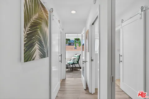 a view of a hallway with wooden floor and a bathroom